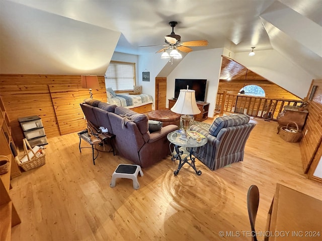 living room featuring ceiling fan, lofted ceiling, wooden walls, and light hardwood / wood-style flooring