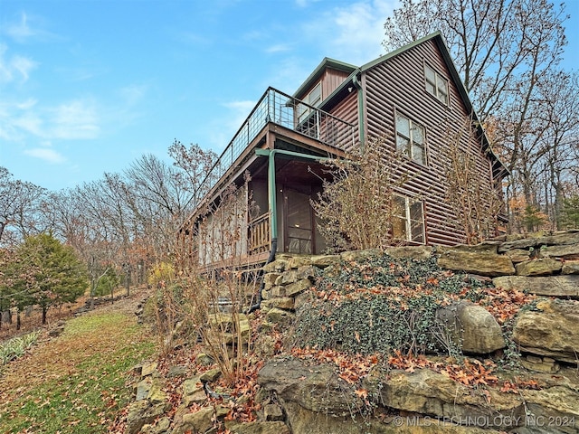 view of property exterior featuring a balcony and a sunroom