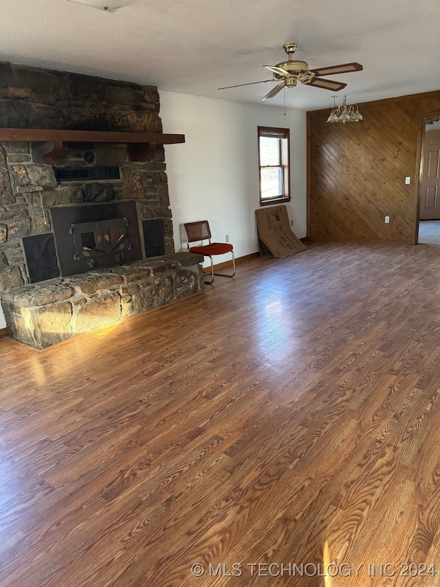 unfurnished living room with hardwood / wood-style floors, a fireplace, wooden walls, and ceiling fan