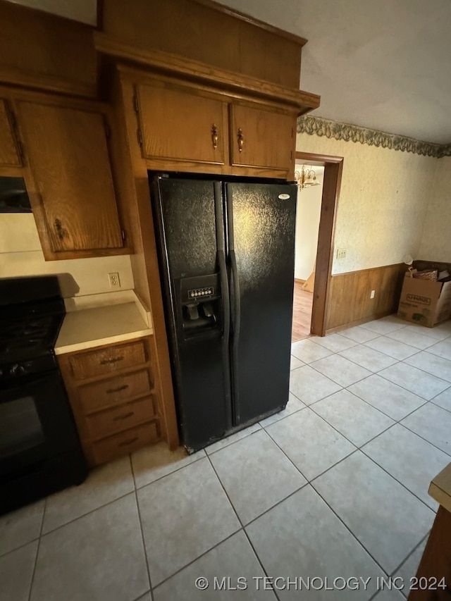 kitchen featuring wood walls, light tile patterned floors, extractor fan, and black appliances