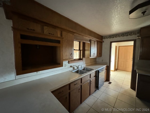 kitchen with black dishwasher, sink, light tile patterned floors, and a textured ceiling