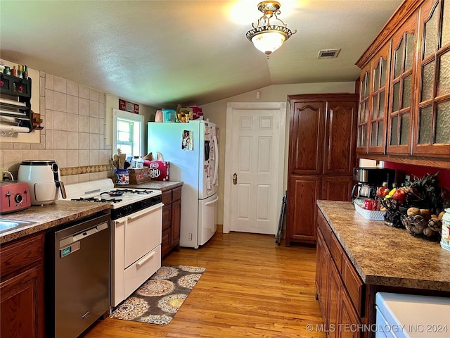 kitchen with white appliances, light hardwood / wood-style flooring, vaulted ceiling, and backsplash