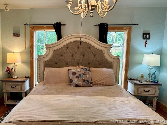 bedroom featuring a chandelier, dark hardwood / wood-style floors, and multiple windows