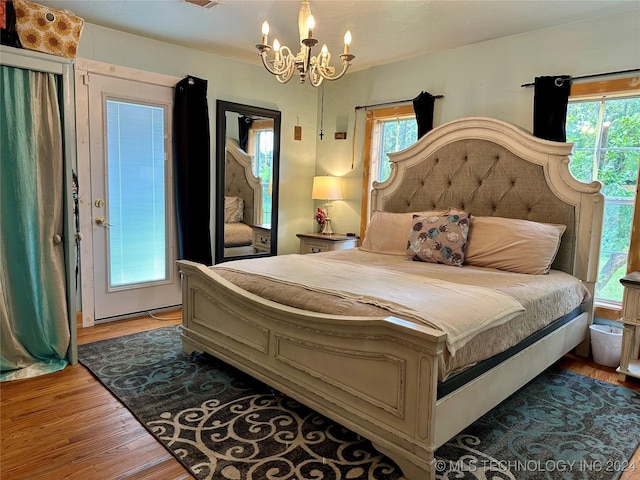 bedroom featuring light hardwood / wood-style floors, an inviting chandelier, and multiple windows