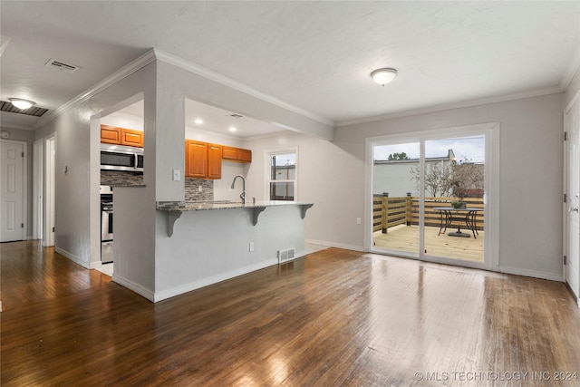 kitchen with backsplash, a kitchen breakfast bar, crown molding, hardwood / wood-style flooring, and kitchen peninsula