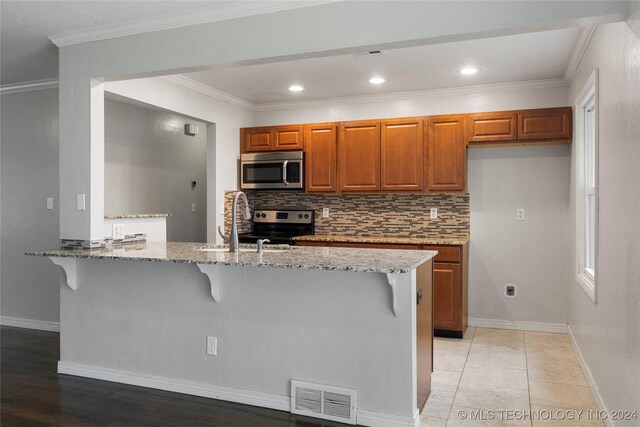 kitchen with light stone countertops, sink, light hardwood / wood-style floors, a breakfast bar, and appliances with stainless steel finishes