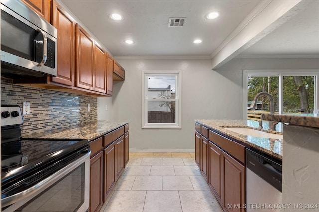 kitchen featuring light stone countertops, appliances with stainless steel finishes, backsplash, ornamental molding, and sink