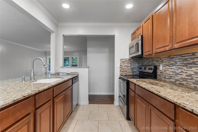 kitchen featuring light stone counters, sink, ornamental molding, and appliances with stainless steel finishes