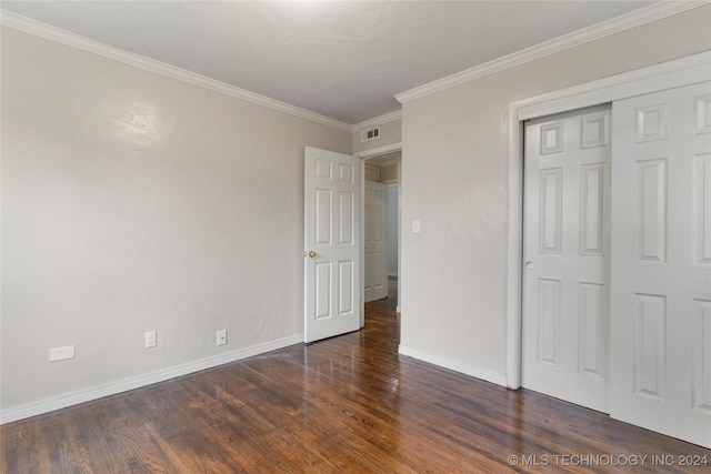 unfurnished bedroom featuring a closet, crown molding, and dark hardwood / wood-style flooring