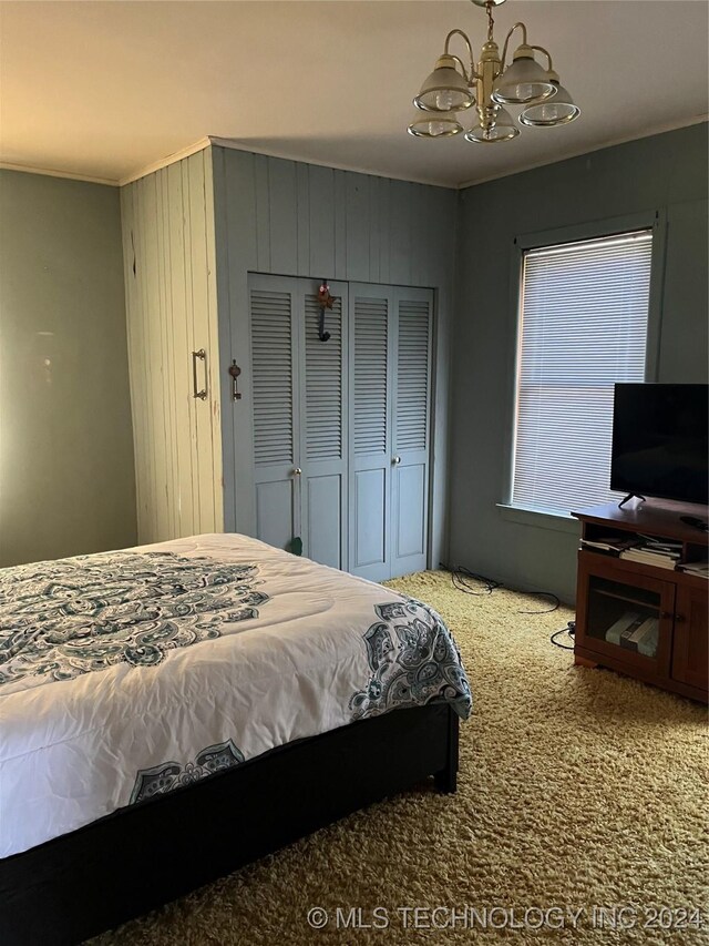 carpeted bedroom featuring an inviting chandelier, a closet, and wooden walls