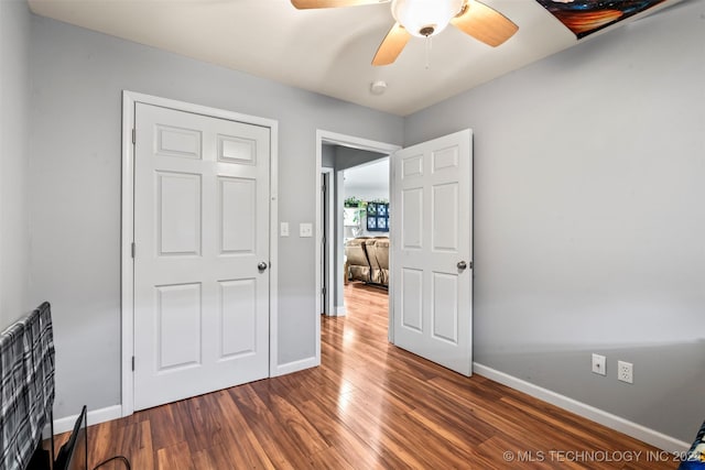 unfurnished bedroom with ceiling fan and dark hardwood / wood-style flooring