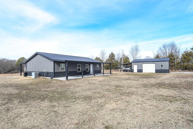 back of house featuring a garage, an outdoor structure, and a lawn