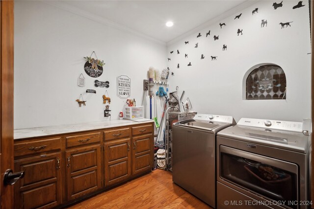 7133 S 425th Rd, Inola, OK 74036 - clothes washing area featuring cabinet space, washing machine and dryer, ornamental molding, and light wood-type flooring