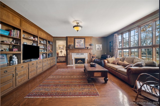 living room featuring dark hardwood / wood-style flooring, built in features, ornamental molding, and a premium fireplace