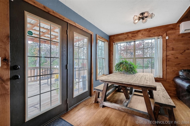 entryway featuring an AC wall unit, a wealth of natural light, wooden walls, and light hardwood / wood-style floors