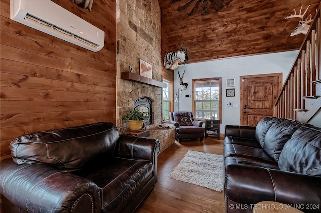 living room with high vaulted ceiling, wooden walls, hardwood / wood-style flooring, a fireplace, and a wall unit AC