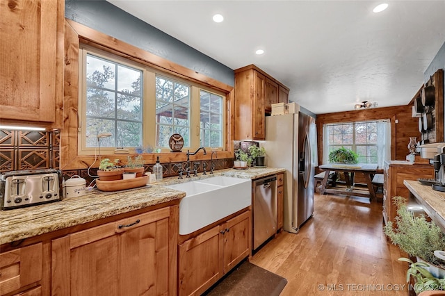 kitchen featuring light stone countertops, sink, light hardwood / wood-style floors, and appliances with stainless steel finishes