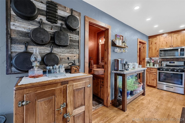 kitchen featuring tasteful backsplash, appliances with stainless steel finishes, and light hardwood / wood-style flooring