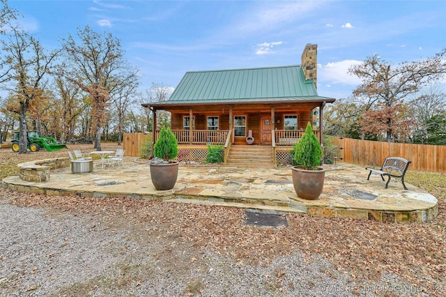 view of front of property featuring covered porch, an outdoor fire pit, and a patio area