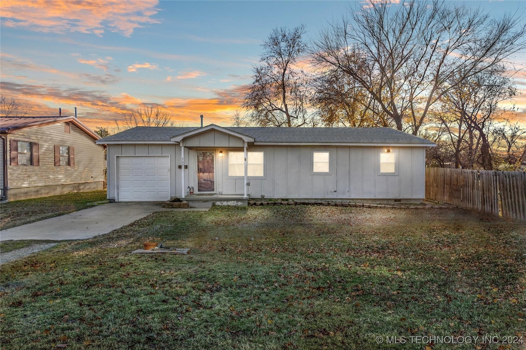 ranch-style house with a garage and a yard