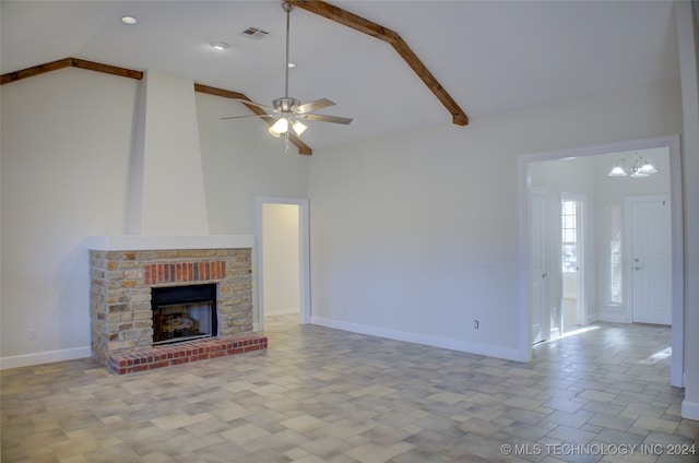 unfurnished living room with ceiling fan with notable chandelier, high vaulted ceiling, and a brick fireplace