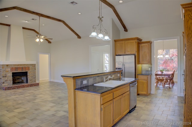 kitchen with appliances with stainless steel finishes, sink, a healthy amount of sunlight, and an island with sink