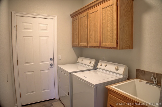 washroom featuring cabinets, sink, and washer and dryer