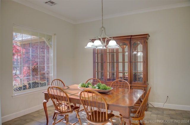 dining space with crown molding and a chandelier