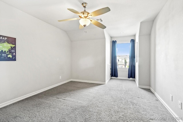 carpeted spare room with ceiling fan and vaulted ceiling