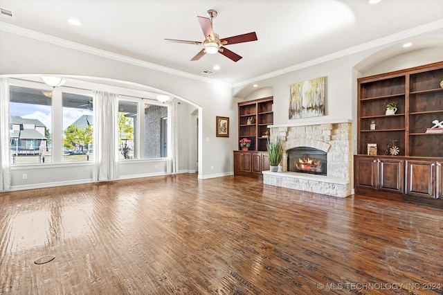 unfurnished living room featuring ceiling fan, ornamental molding, a fireplace, and dark wood-type flooring