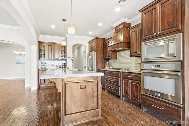 kitchen with tasteful backsplash, stainless steel appliances, a kitchen island with sink, dark wood-type flooring, and sink