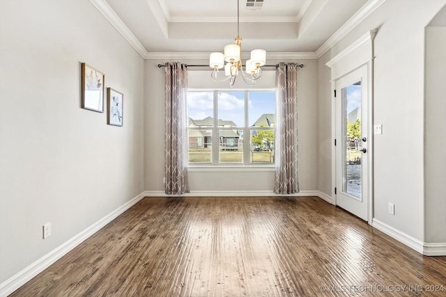 unfurnished dining area featuring a chandelier, wood-type flooring, a tray ceiling, and crown molding