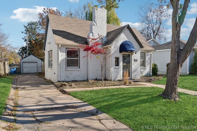 view of front of home featuring a front yard, a garage, and an outbuilding