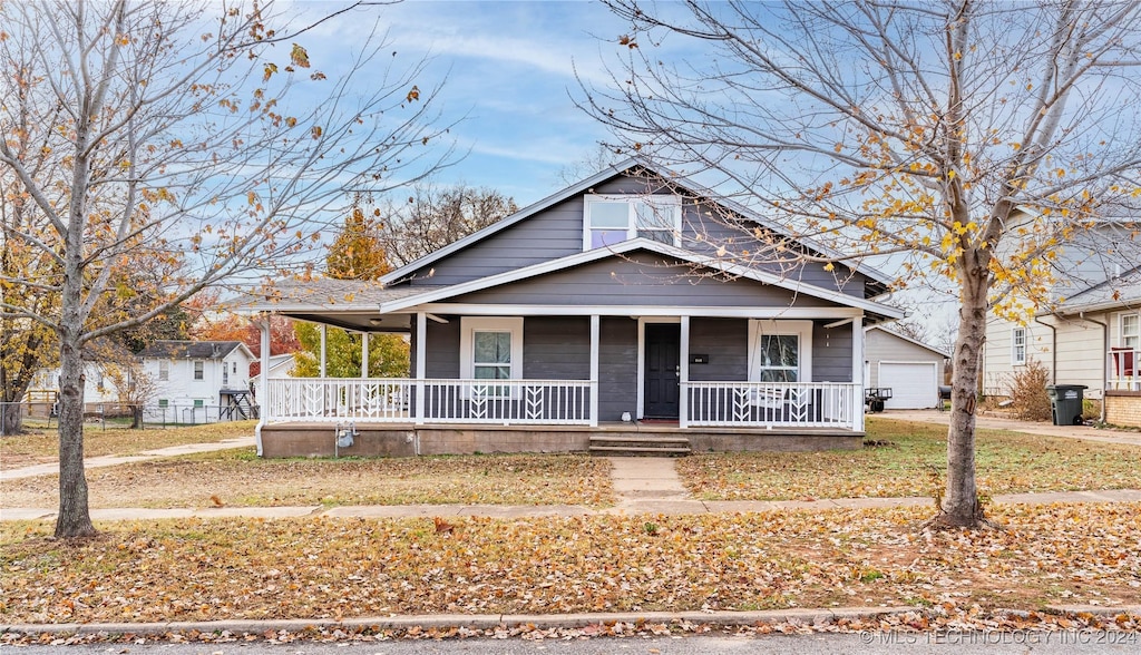 view of front of property featuring covered porch, a garage, and an outdoor structure