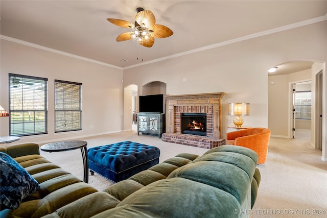 carpeted living room featuring a brick fireplace, ceiling fan, and crown molding