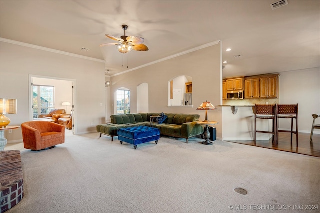 living room with light carpet, a wealth of natural light, crown molding, and ceiling fan