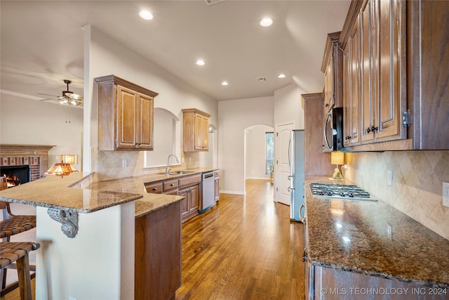 kitchen featuring hardwood / wood-style floors, a kitchen breakfast bar, dark stone countertops, appliances with stainless steel finishes, and kitchen peninsula