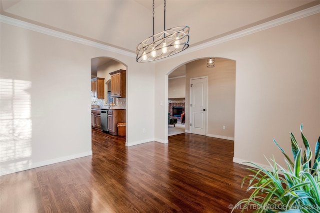 unfurnished dining area with a fireplace, dark hardwood / wood-style flooring, and crown molding