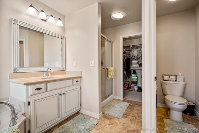 bathroom with tile patterned flooring, vanity, toilet, and a shower with shower door