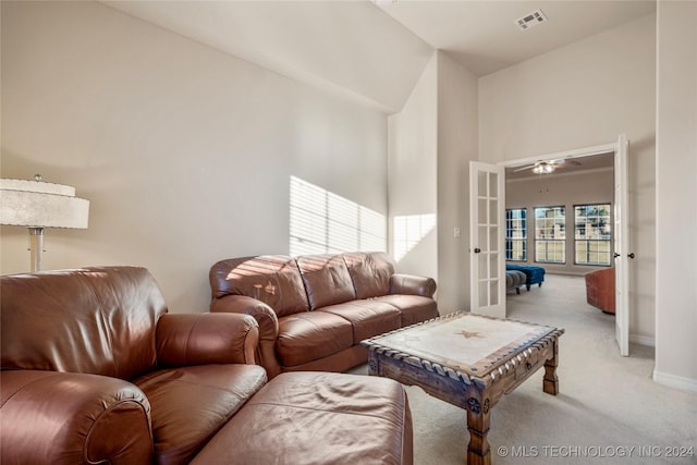 living room with ceiling fan, french doors, high vaulted ceiling, and light colored carpet