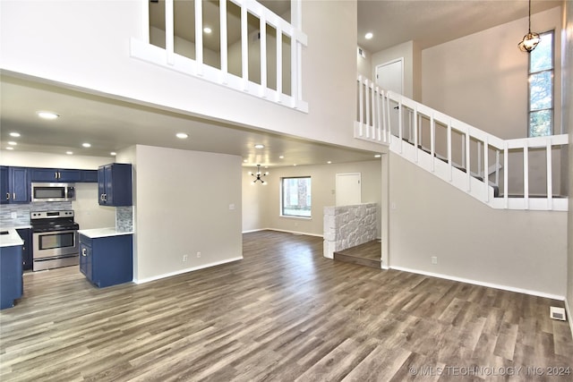 unfurnished living room featuring a notable chandelier, dark hardwood / wood-style flooring, and a towering ceiling