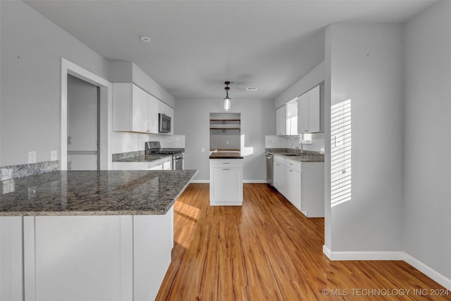 kitchen with white cabinets, sink, light wood-type flooring, appliances with stainless steel finishes, and kitchen peninsula