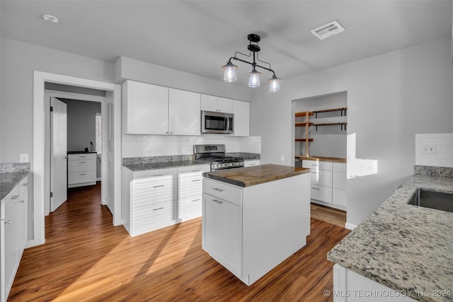 kitchen featuring white cabinetry, a kitchen island, stainless steel appliances, and wood-type flooring