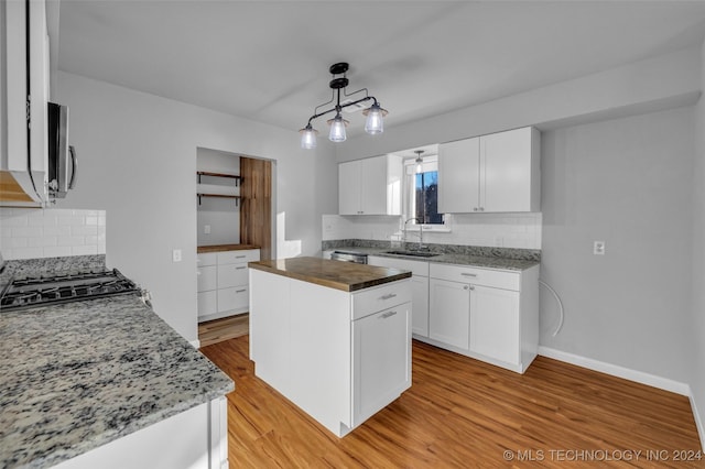 kitchen featuring white cabinets, decorative light fixtures, light hardwood / wood-style floors, and sink