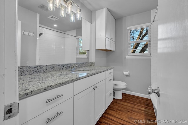 bathroom featuring tiled shower, hardwood / wood-style flooring, toilet, and plenty of natural light