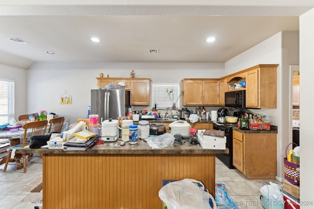 kitchen featuring a center island, sink, stainless steel fridge, lofted ceiling, and a kitchen bar