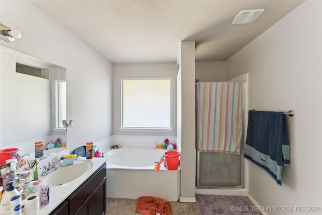 bathroom with vanity, a textured ceiling, and shower with separate bathtub