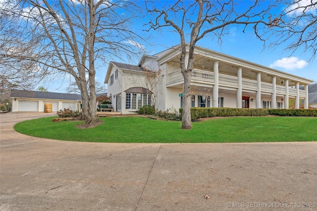 greek revival inspired property featuring a balcony and a front yard