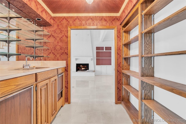 bar with light tile patterned flooring, sink, crown molding, and a fireplace