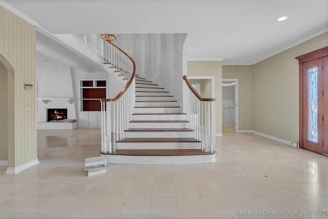 entrance foyer featuring ornamental molding and a fireplace